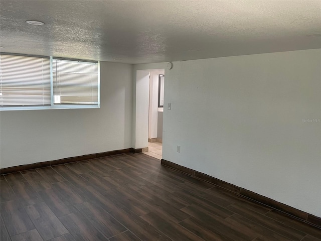 unfurnished room with a textured ceiling and dark wood-type flooring