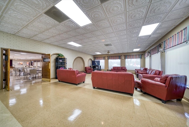 living area featuring an ornate ceiling, brick wall, and tile patterned floors