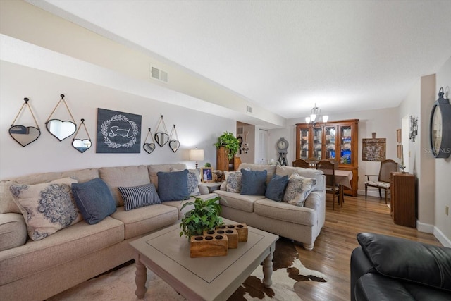 living room featuring light wood-style flooring, visible vents, and a notable chandelier