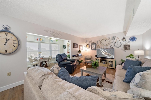 living area with a textured ceiling, baseboards, and wood finished floors