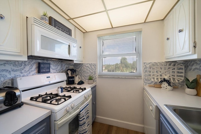 kitchen featuring white appliances, baseboards, light countertops, and decorative backsplash