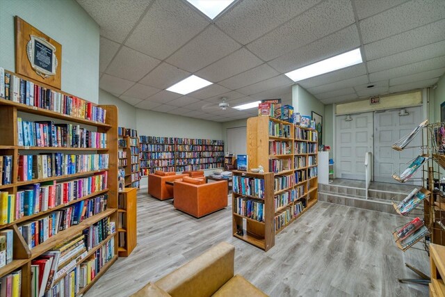 living area with a drop ceiling and light wood-type flooring