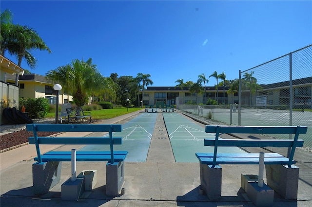 view of home's community featuring a tennis court, fence, and shuffleboard