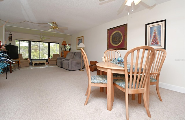 carpeted dining area with a textured ceiling and ceiling fan