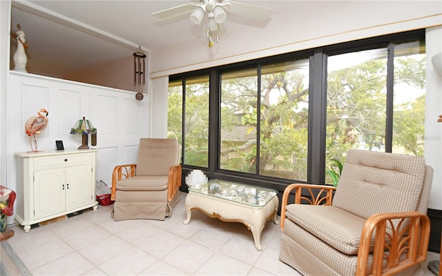 living area featuring light tile patterned flooring, a ceiling fan, and a decorative wall