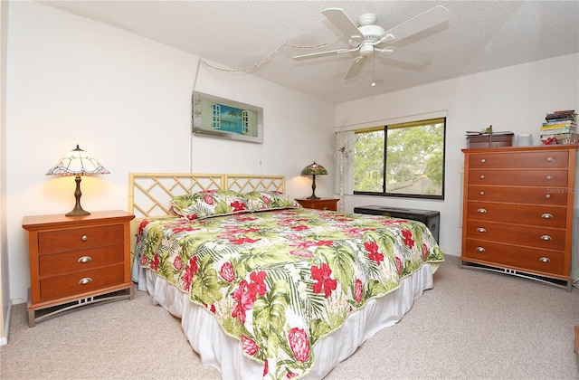 bedroom with light carpet, ceiling fan, and a textured ceiling