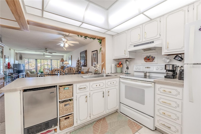 kitchen with a peninsula, white appliances, under cabinet range hood, white cabinetry, and a sink