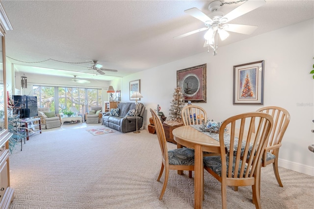 dining room with light carpet, a textured ceiling, baseboards, and ceiling fan