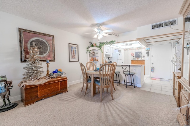dining area with light colored carpet, light tile patterned floors, a textured ceiling, ceiling fan, and visible vents