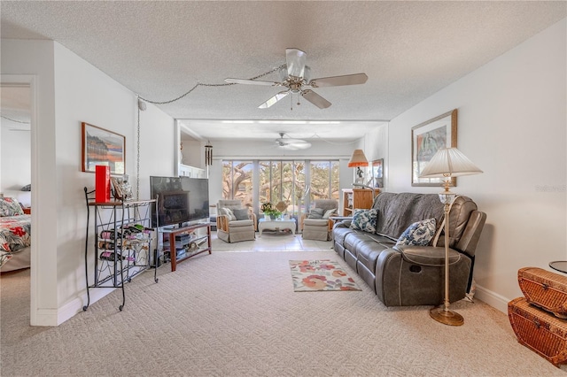 carpeted living room featuring a textured ceiling, baseboards, and a ceiling fan