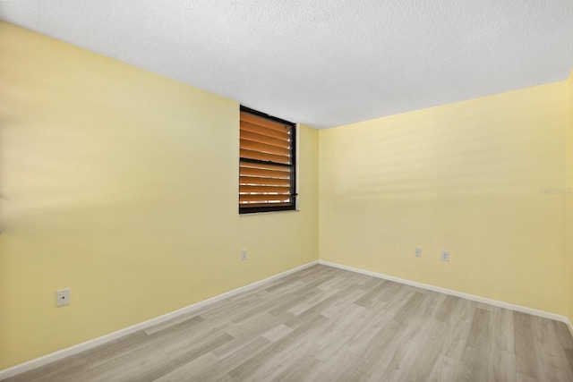 spare room with light hardwood / wood-style floors and a textured ceiling