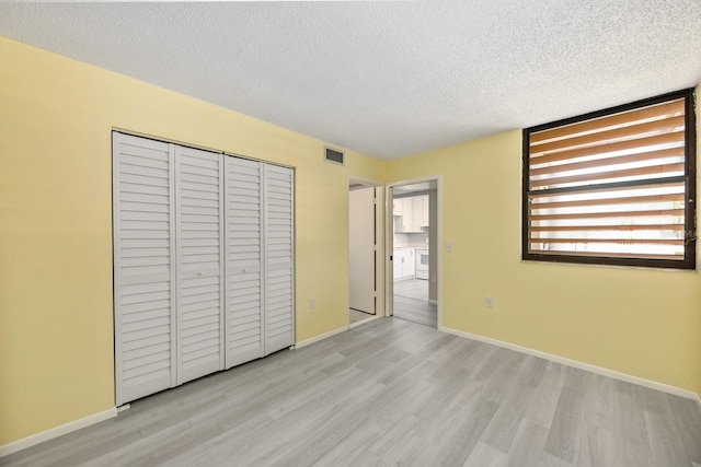 unfurnished bedroom featuring a textured ceiling, light hardwood / wood-style floors, and a closet