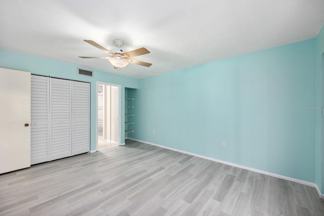 unfurnished bedroom with a textured ceiling, light hardwood / wood-style flooring, a closet, and ceiling fan