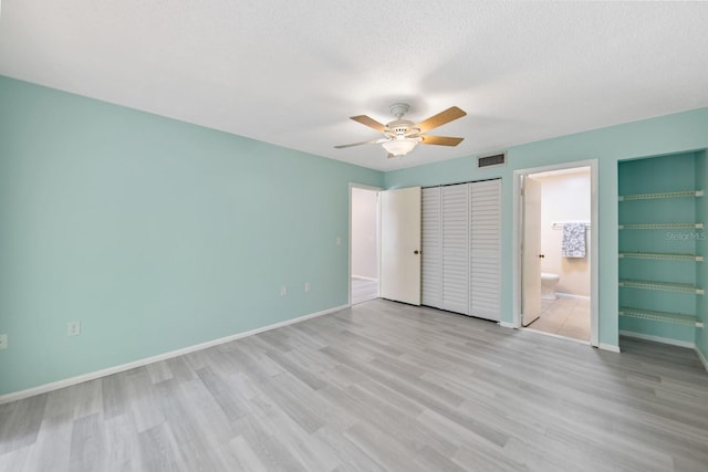 unfurnished bedroom with ceiling fan, light wood-type flooring, a textured ceiling, and ensuite bath