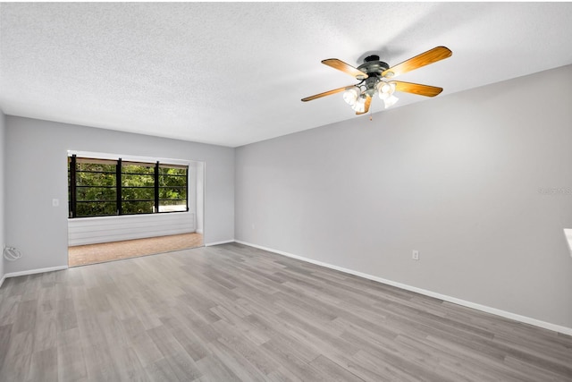 spare room featuring ceiling fan, light hardwood / wood-style floors, and a textured ceiling