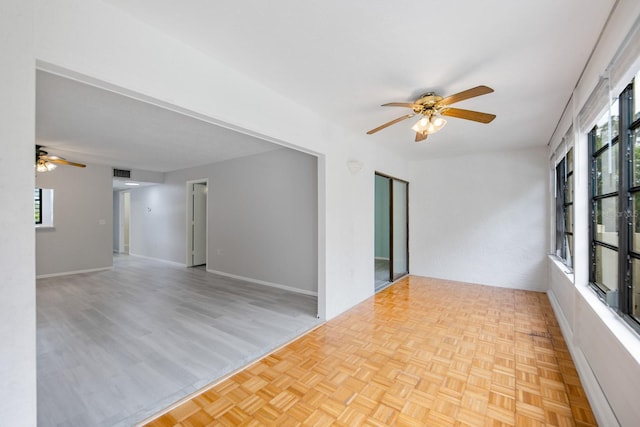 unfurnished room with light parquet flooring, a wealth of natural light, and ceiling fan