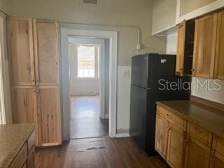 kitchen with dark hardwood / wood-style floors and black fridge