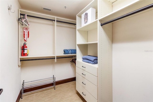 walk in closet featuring light colored carpet