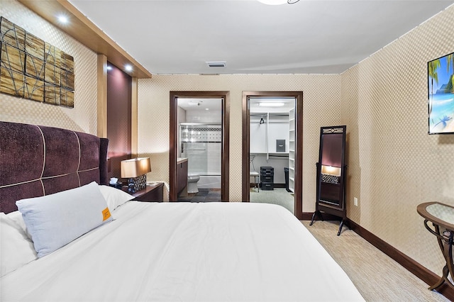 bedroom featuring light colored carpet, connected bathroom, and a spacious closet