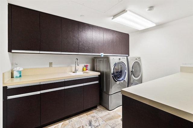 clothes washing area featuring washer and dryer, sink, and cabinets