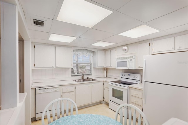 kitchen with white appliances, a drop ceiling, tasteful backsplash, and sink