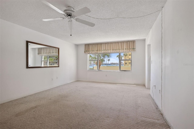 carpeted empty room featuring ceiling fan and a textured ceiling