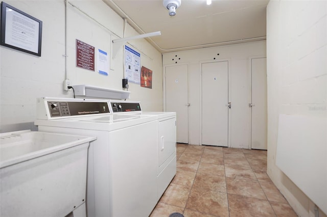 washroom featuring light tile floors, sink, and washer and clothes dryer