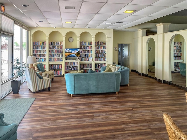 living room featuring dark wood-type flooring and a drop ceiling