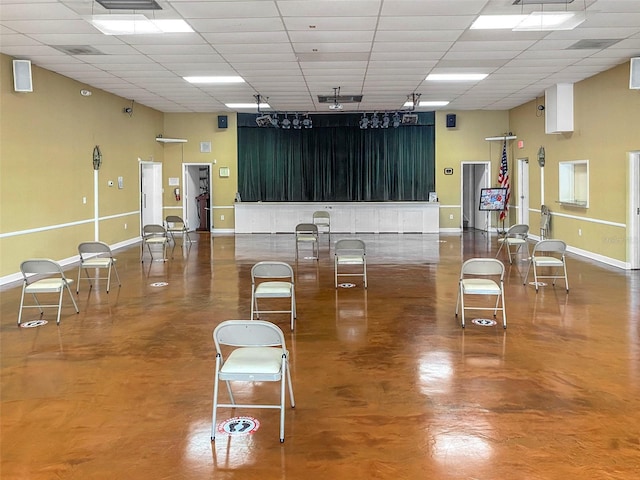 miscellaneous room featuring a towering ceiling and a drop ceiling