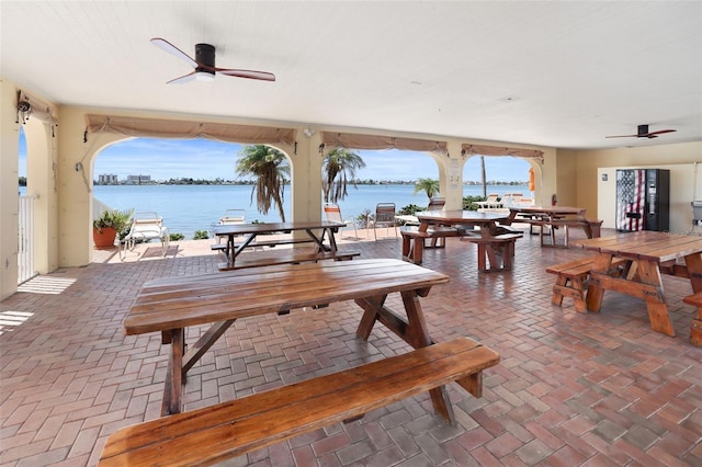 dining space with a water view, a healthy amount of sunlight, and ceiling fan