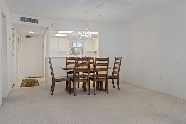 carpeted dining area with a textured ceiling and ceiling fan with notable chandelier