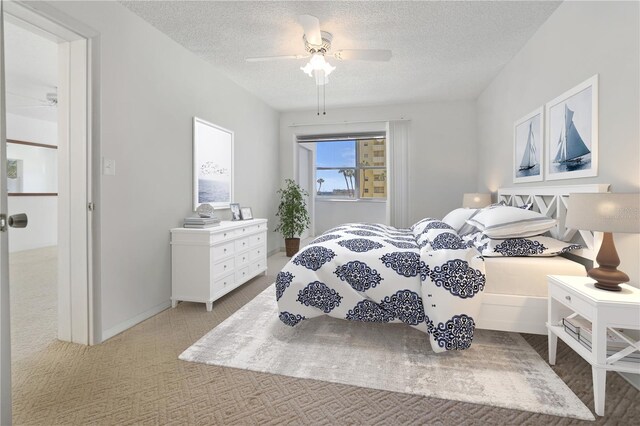 carpeted bedroom featuring a textured ceiling and ceiling fan