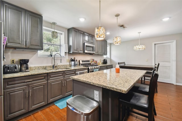 kitchen with a kitchen breakfast bar, a center island, appliances with stainless steel finishes, light wood-type flooring, and sink