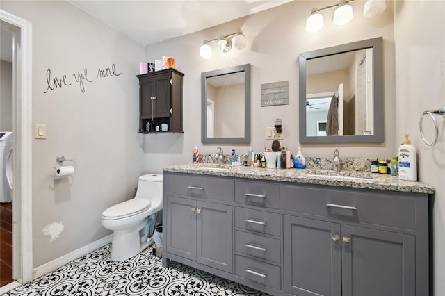 bathroom featuring washer / clothes dryer, toilet, tile floors, and dual vanity