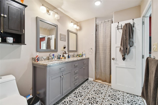 bathroom featuring toilet, double vanity, and tile floors