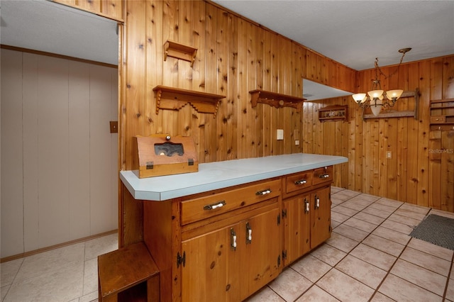 kitchen featuring wood walls, hanging light fixtures, crown molding, light tile floors, and a textured ceiling