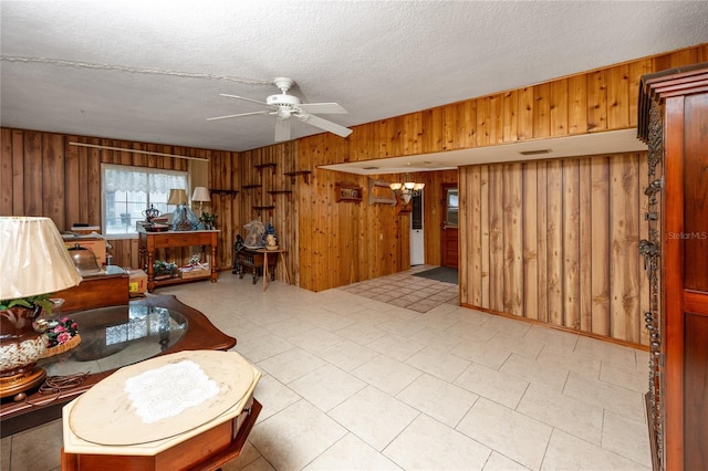 living room with wood walls, ceiling fan, tile floors, and a textured ceiling