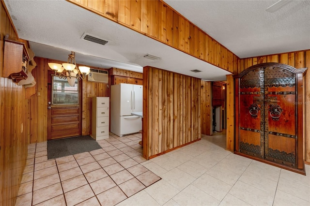 kitchen with white refrigerator, wood walls, and a textured ceiling