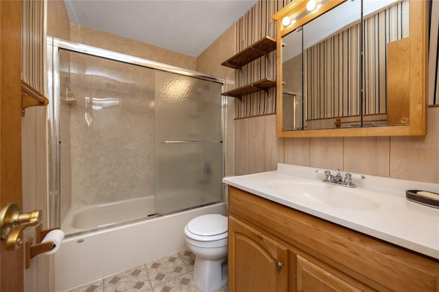 full bathroom featuring tile flooring, a textured ceiling, combined bath / shower with glass door, toilet, and vanity