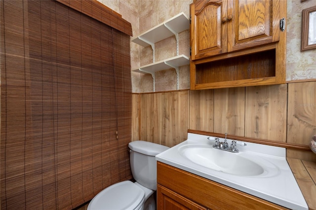 bathroom featuring wooden walls, toilet, and large vanity