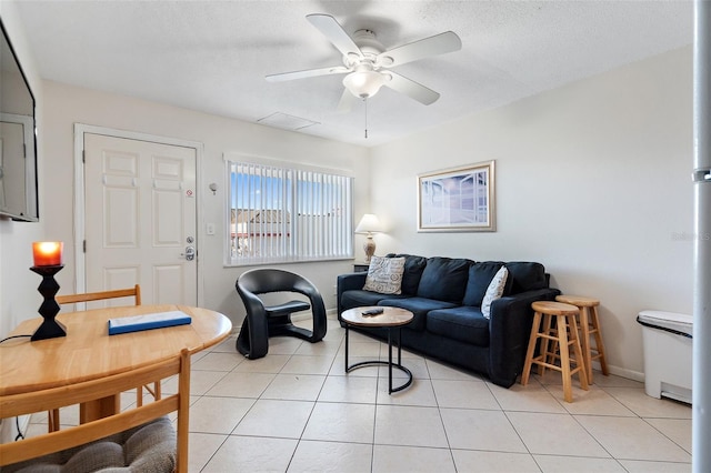 living room with light tile floors, ceiling fan, and a textured ceiling