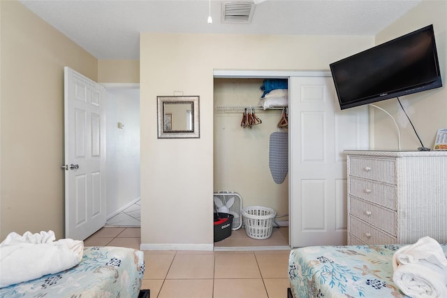 tiled bedroom with a textured ceiling and a closet