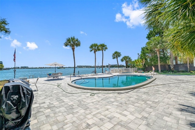 view of swimming pool with a patio area and a water view