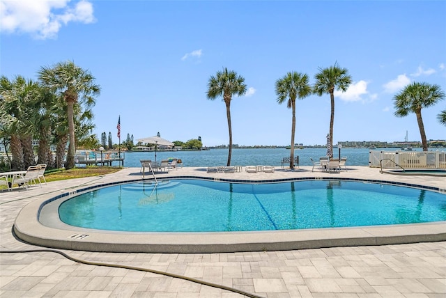 view of pool featuring a water view and a patio