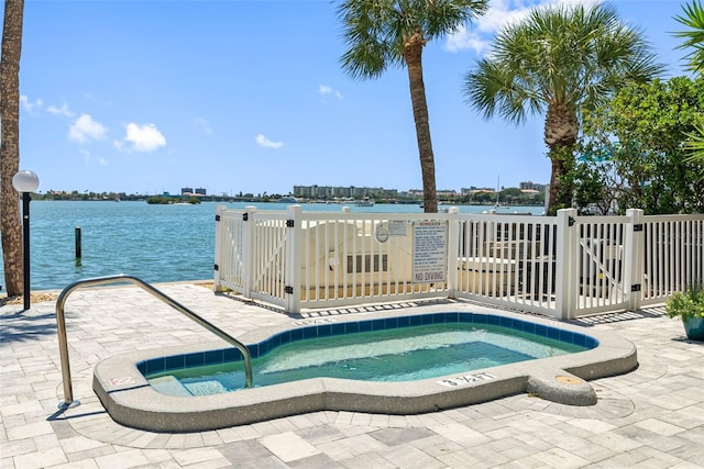 view of swimming pool featuring a patio, a hot tub, and a water view