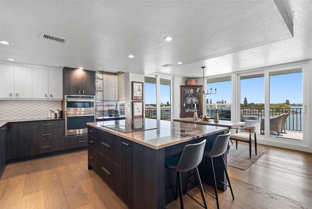 kitchen featuring light hardwood / wood-style flooring, white cabinetry, double oven, and a center island