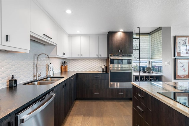 kitchen featuring dark brown cabinets, sink, white cabinetry, appliances with stainless steel finishes, and light hardwood / wood-style floors