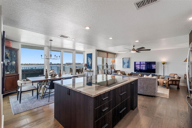 kitchen featuring hardwood / wood-style floors, a kitchen island, a textured ceiling, and black electric cooktop