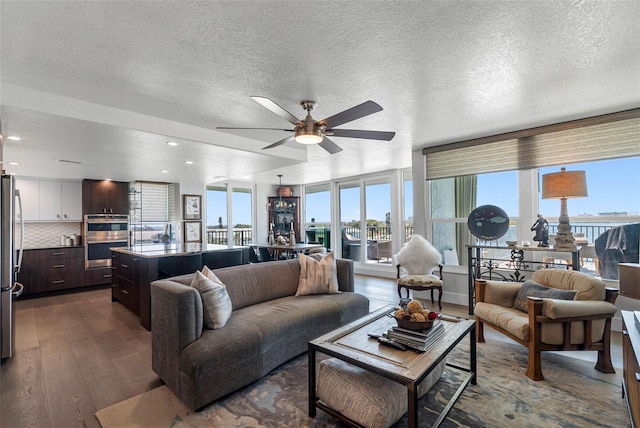 living room featuring ceiling fan, a textured ceiling, and dark hardwood / wood-style flooring