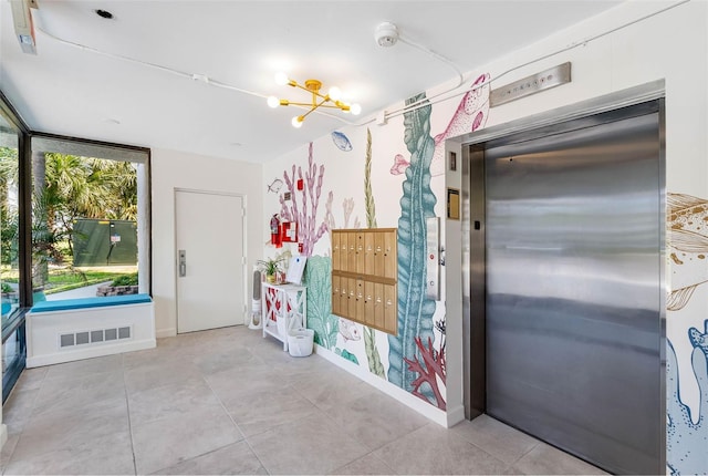 interior space featuring elevator, an inviting chandelier, and light tile patterned floors